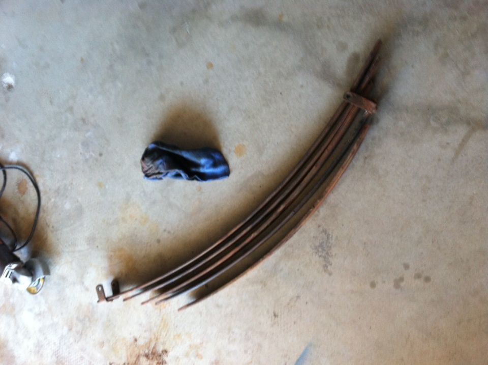 Rusty leaf springs on concrete floor with a blue cloth and grinder