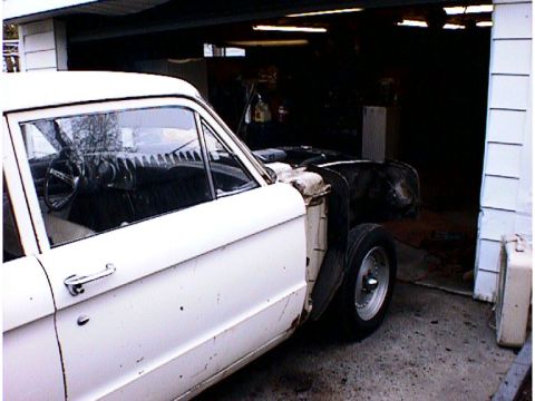 1960 Ford Falcon - A white 1960 Ford Falcon sedan is seen from the front quarter angle, with its hood removed, inside a garage.