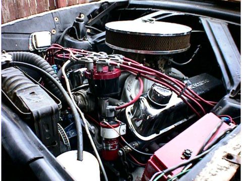 1960 Ford Falcon - Close-up view of a car's engine bay, red spark plug wires and chrome valve covers.