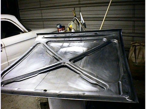 1960 Ford Falcon - Underside of a car hood with visible bracing. A white car is partially visible in the background.