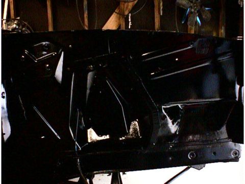 1960 Ford Falcon - The black car chassis shows signs of wear and tear, with rust and damage visible on its structure.