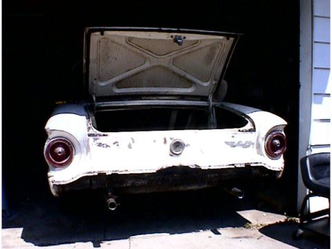 1960 Ford Falcon - The rear of a 1957 Ford Thunderbird is shown with its trunk open, revealing its interior and the car's aged condition.