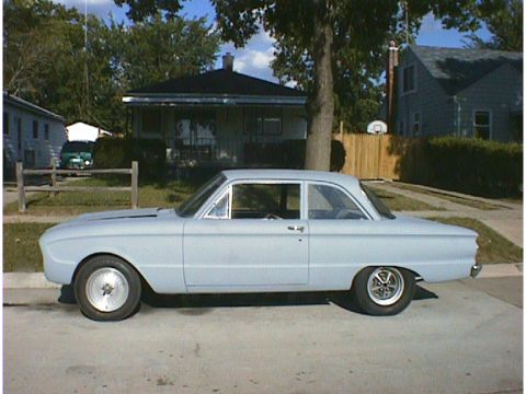 1960 Ford Falcon - A light blue 1960 Ford Falcon sedan with a primer finish and custom wheels sits parked on a residential street.