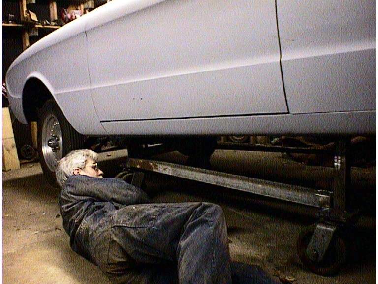 Person working under a 1960 Ford Falcon, which is on a lift