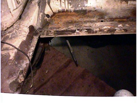 1960 Ford Falcon - Close-up of a heavily rusted car floor pan showing significant deterioration and a hole.