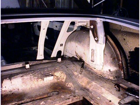 1960 Ford Falcon - The rear interior of a vehicle shows significant rust and exposed structural elements around the wheel well.