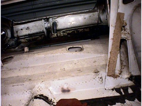 1960 Ford Falcon - The interior of a white car shows a dirty floor and side panel, with some visible structural components.