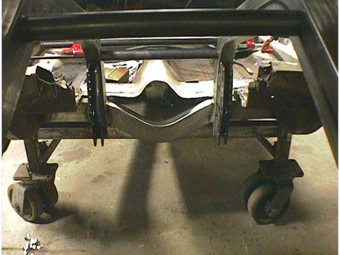 1960 Ford Falcon - The rear frame of a vehicle is elevated on casters, revealing its undercarriage and suspension system.