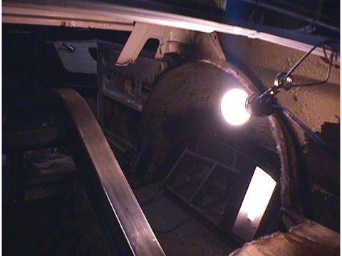 1960 Ford Falcon - Work light illuminates the interior of a car's rear wheel well during what appears to be a restoration project.