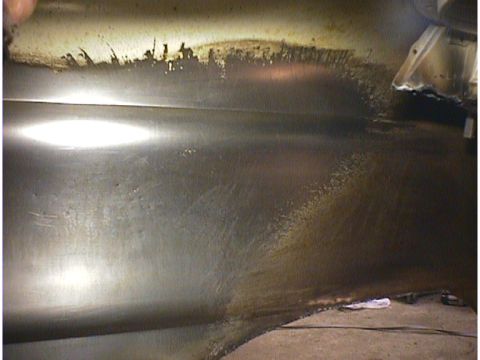 1960 Ford Falcon - The underside of a vehicle shows dirt and grime buildup along the frame and body panels.