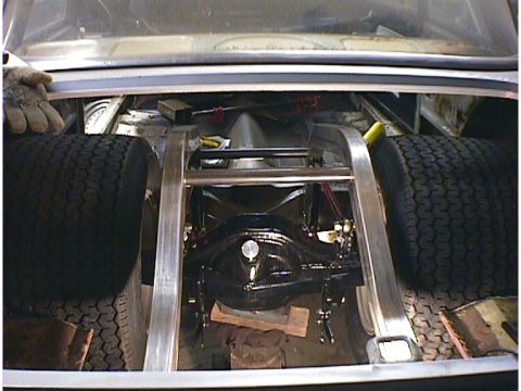 1960 Ford Falcon - The rear axle and suspension components are visible inside the trunk of a car, with two tires flanking the assembly.
