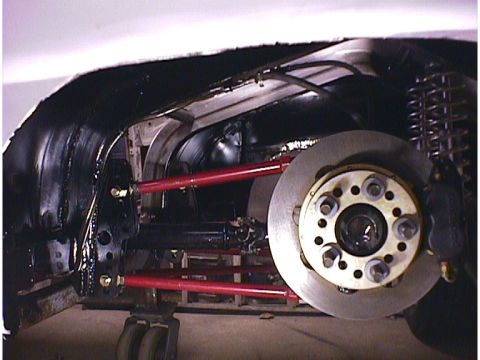1960 Ford Falcon - Close-up view of a modified rear suspension system, red control arms and a disc brake setup.