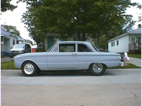 1960 Ford Falcon - A 1960 Ford Falcon sedan is parked on a residential street, showing its side profile with custom wheels.