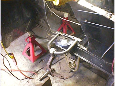 1960 Ford Falcon - Close-up of a car's front suspension components being worked on, supported by red jack stands.