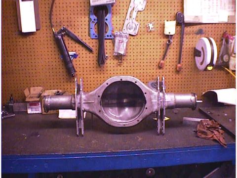 1960 Ford Falcon - A rear axle assembly sits on a workbench, with various tools and parts hanging on the pegboard wall.