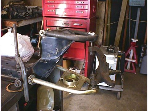 1960 Ford Falcon - Front suspension components are shown disassembled in a workshop setting, with a red toolbox and other equipment visible.