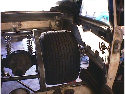 1960 Ford Falcon - The interior of a vehicle under construction, showing a large tire and rear axle with suspension components.