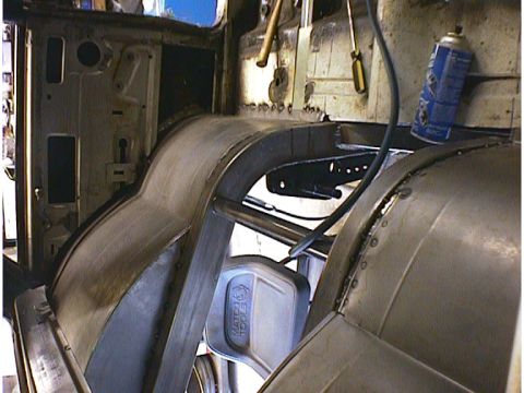 1960 Ford Falcon - The interior of a vehicle is shown during a repair process, focusing on the floor and wheel well areas.