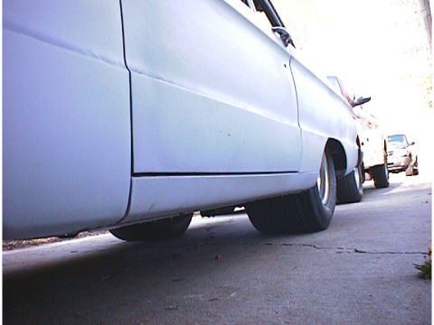 1960 Ford Falcon - A light blue car is parked on a cracked asphalt surface, with other vehicles in the background.
