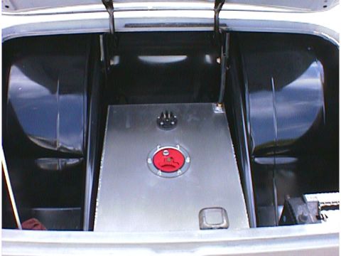 1960 Ford Falcon - The trunk of a vehicle contains a large, custom metal fuel tank with a red cap and black fittings.