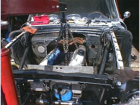 1960 Ford Falcon - Engine removal in progress for a 1960 Ford Falcon, showing the open engine bay and hoist chains.