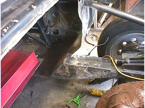 1960 Ford Falcon - Close-up view of a car's chassis and wheel, showing exposed wiring and repair work on the frame.