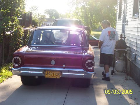 1960 Ford Falcon - A man stands by a red 1960 Ford Falcon in a driveway, with a barbecue grill nearby.