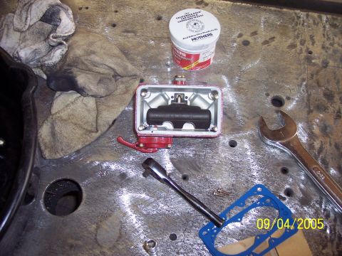 1960 Ford Falcon - A brake master cylinder is disassembled on a workbench, surrounded by tools and cleaning supplies.