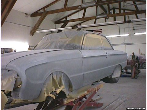 1960 Ford Falcon - A classic car is being prepped for paint in a body shop, with its bodywork covered in primer and masked for protection.