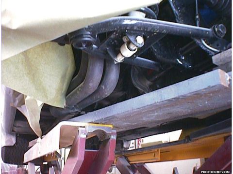 1960 Ford Falcon - A close-up view of a vehicle's undercarriage, revealing exhaust headers and suspension parts while on a lift.