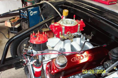 1960 Ford Falcon - Close-up of an engine bay red Ford valve covers and a prominent red carburetor, with a Miller welding machine in the background.