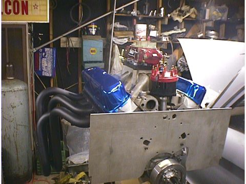 1960 Ford Falcon - A V8 engine with custom headers and ignition components is shown in a workshop setting.