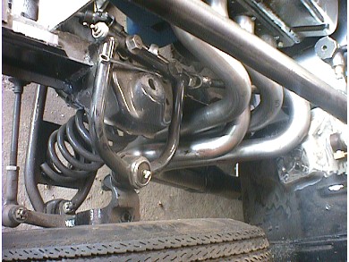 1960 Ford Falcon - Close-up view of a vehicle's front suspension system and custom exhaust headers.
