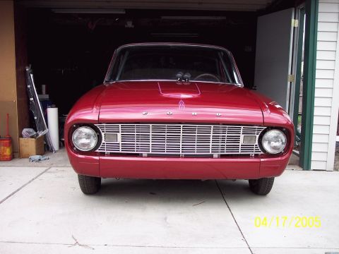 1960 Ford Falcon - This 1960 Ford Falcon is presented in a front-facing view, highlighting its distinctive chrome grille and a prominent hood scoop.