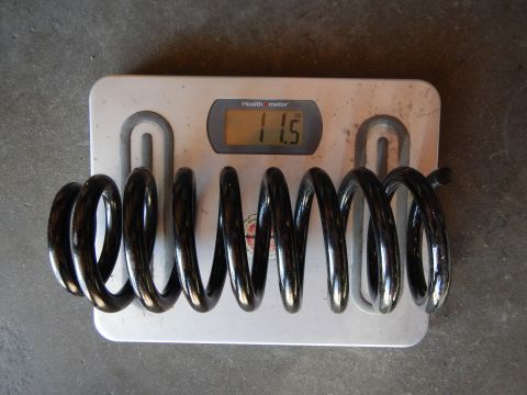 2003 Ford Crown Victoria - black automotive coil spring stretched across a Health o meter bathroom scale, which reads 11.5 pounds.