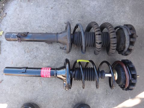 2003 Ford Taurus - Comparison of a used strut assembly and a new one, likely for a vehicle's suspension system.