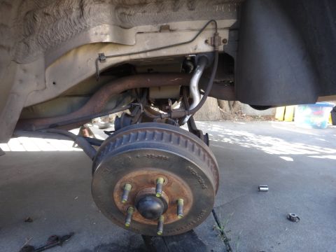 2003 Ford Taurus - Close-up view of a vehicle's rear suspension and brake drum assembly, showing various mechanical parts.