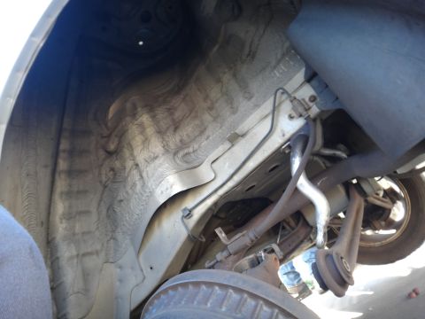 2003 Ford Taurus - Close-up view of the undercarriage, focusing on the rear suspension and wheel well area.