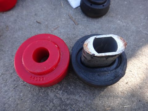 2003 Ford Taurus - Two automotive bushings, one red and one black, are shown on a concrete surface.