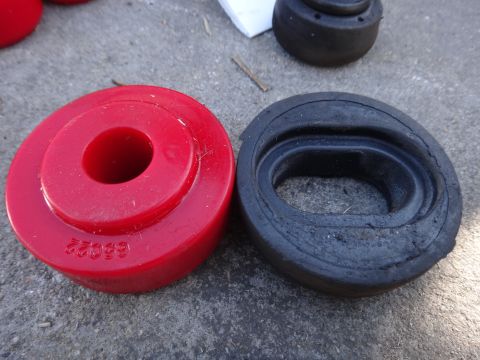 2003 Ford Taurus - Comparison of a red polyurethane bushing and a worn black rubber bushing, likely for vehicle suspension.