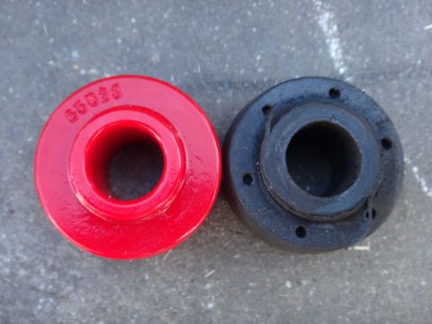 2003 Ford Taurus - Two bushings, one red and one black, are shown side-by-side on a textured gray surface.