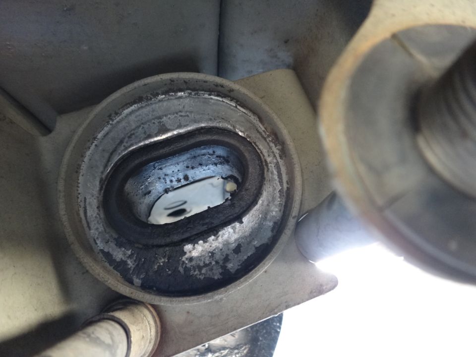 Close-up of a worn strut mount bushing with metal and rubber components visible