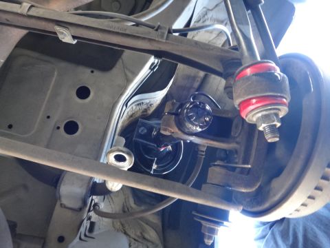 2003 Ford Taurus - Close-up of automotive suspension parts, including a brake rotor and linkage, viewed from below.