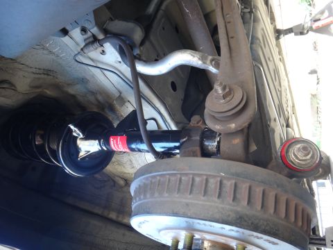 2003 Ford Taurus - Close-up view of a vehicle's rear suspension strut and drum brake assembly, showing suspension components and brake hardware.