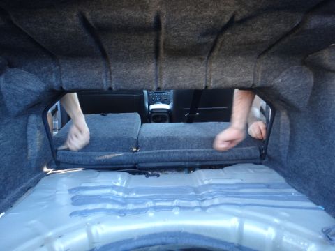 2003 Ford Taurus - Hands are seen working inside the trunk of a car with the rear seats folded down.