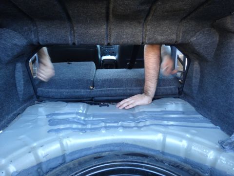 2003 Ford Taurus - Looking into the trunk of a car, with the spare tire well and rear seats visible.
