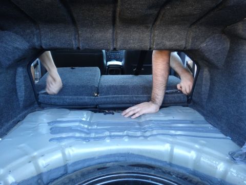 2003 Ford Taurus - Hands are seen reaching into the back seat from the trunk of a car.