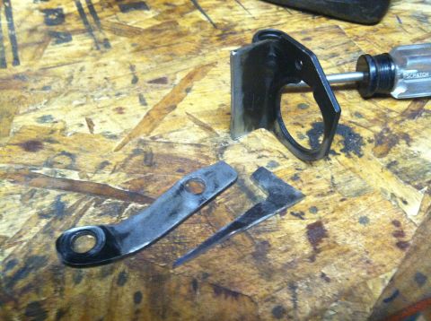 1975 Ford Courier - A broken metal bracket lies on a workbench next to a screwdriver.