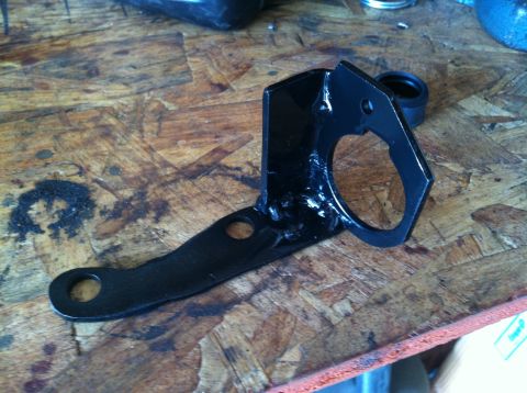 1975 Ford Courier - A black metal bracket, likely a replacement part, rests on a textured wooden surface.