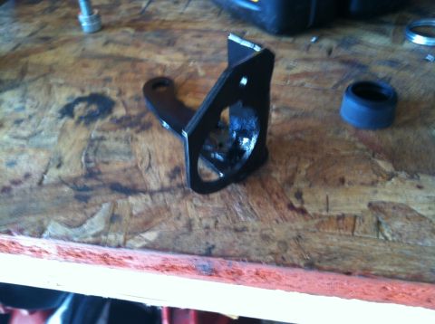 1975 Ford Courier - A close-up view of a black metal bracket and a blue rubber ring on a wooden workbench.